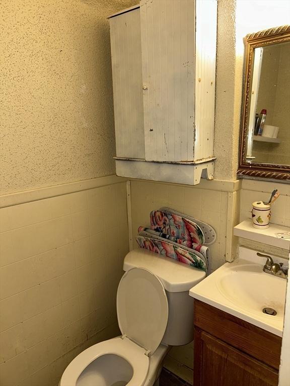 bathroom with vanity, toilet, and tile walls