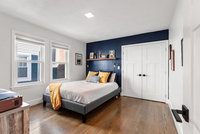 bedroom with a closet, dark wood finished floors, and baseboards