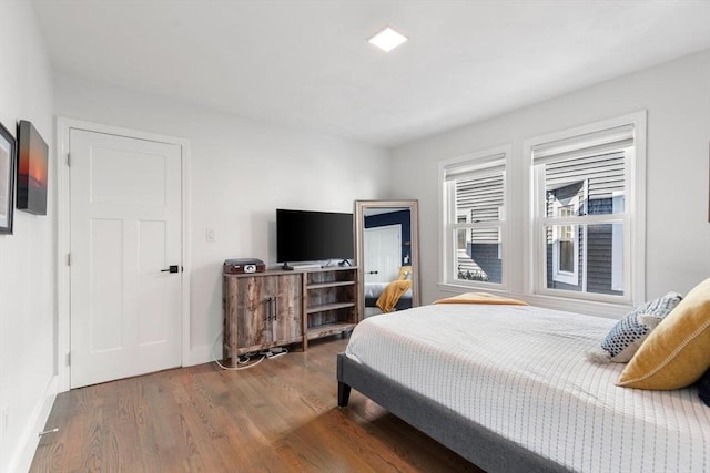 bedroom with dark wood finished floors and baseboards