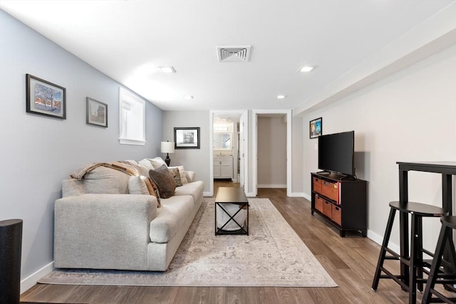 living room featuring visible vents, baseboards, and wood finished floors