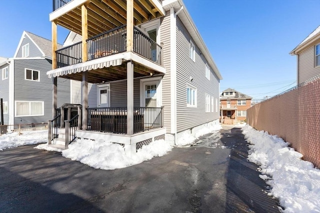 snow covered rear of property featuring a balcony