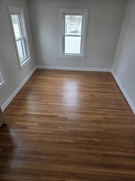 empty room with dark hardwood / wood-style flooring and a wealth of natural light