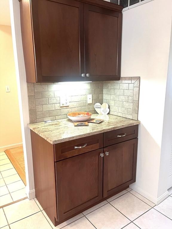 38 Hammond Pl Unit 38, Woburn, MA 01801 - kitchen with backsplash, light tile patterned flooring, light stone countertops, and dark brown cabinets