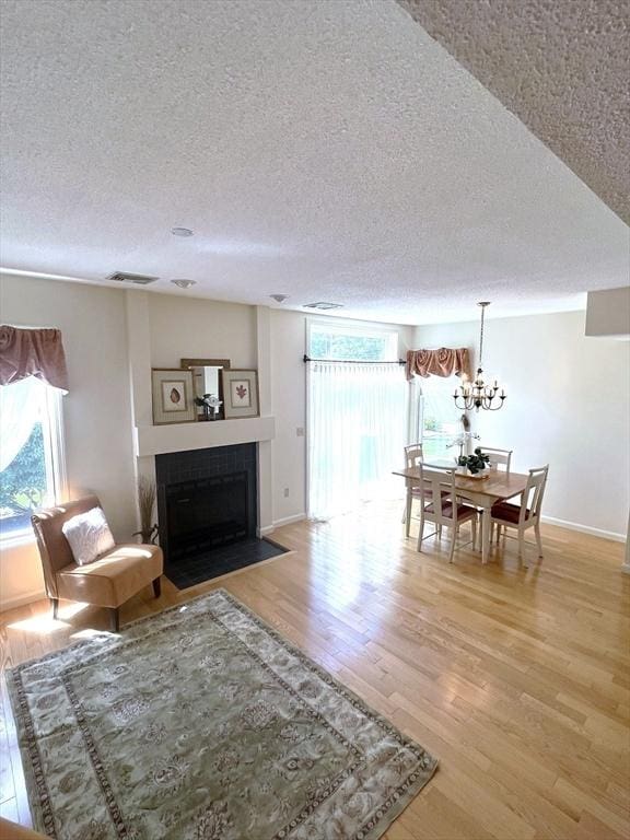 38 Hammond Pl Unit 38, Woburn, MA 01801 - living room featuring a textured ceiling, light wood finished floors, a fireplace with flush hearth, and a chandelier