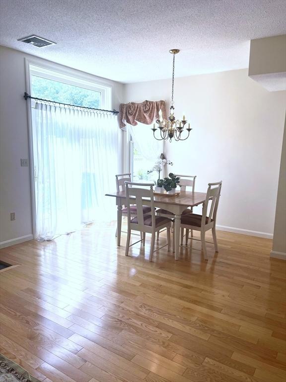38 Hammond Pl Unit 38, Woburn, MA 01801 - dining area with light wood-type flooring, a chandelier, and a textured ceiling