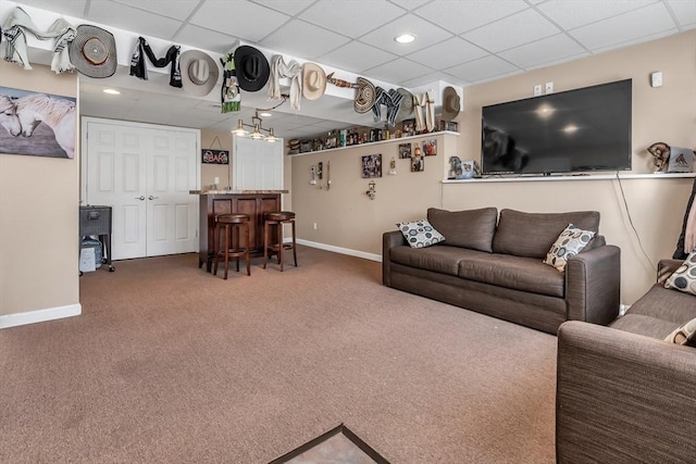 carpeted living room featuring a paneled ceiling and bar