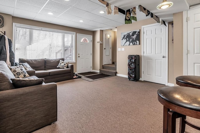 carpeted living room featuring a drop ceiling