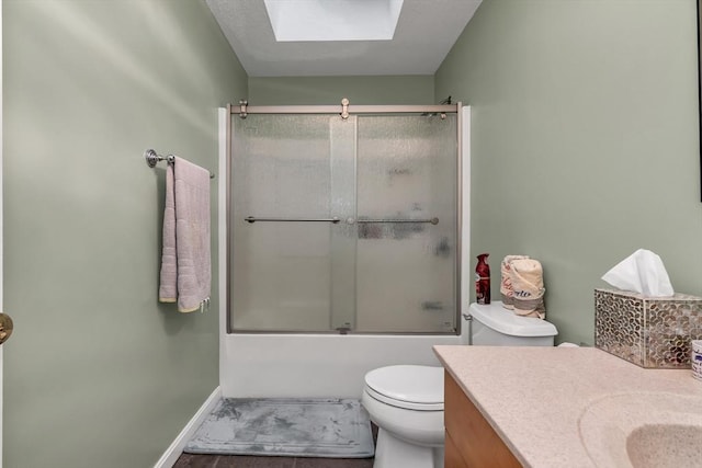 full bathroom featuring a skylight, vanity, combined bath / shower with glass door, and toilet