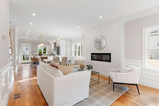 162 Swanton St Unit 162, Winchester, MA 01890 - living room featuring a decorative wall, healthy amount of natural light, a premium fireplace, light wood-style floors, and crown molding