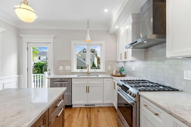 162 Swanton St Unit 162, Winchester, MA 01890 - kitchen with wall chimney exhaust hood, stainless steel appliances, a sink, crown molding, and white cabinets