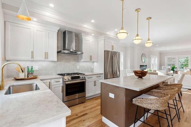162 Swanton St Unit 162, Winchester, MA 01890 - kitchen with stainless steel appliances, wall chimney exhaust hood, a sink, light wood-style flooring, and crown molding