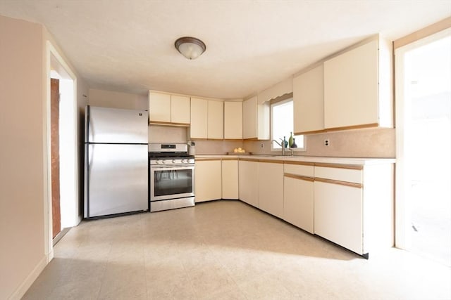 208 Green St, Weymouth, MA 02191 - kitchen featuring stainless steel appliances, light countertops, cream cabinetry, and a sink