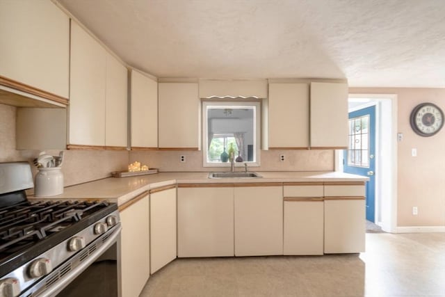 208 Green St, Weymouth, MA 02191 - kitchen featuring gas stove, cream cabinets, a sink, and tasteful backsplash