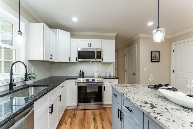 kitchen featuring decorative light fixtures, sink, stainless steel appliances, and white cabinets