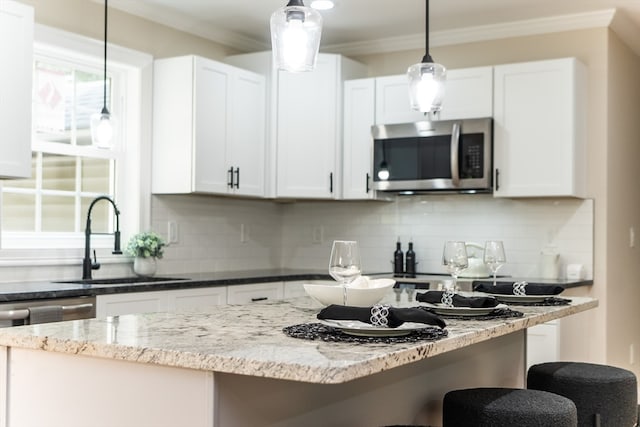 kitchen with sink, white cabinetry, stainless steel appliances, a breakfast bar area, and decorative backsplash