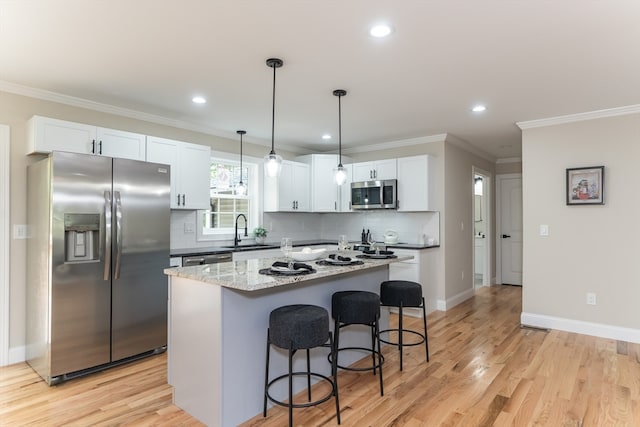 kitchen featuring white cabinets, sink, appliances with stainless steel finishes, a center island, and light wood-type flooring