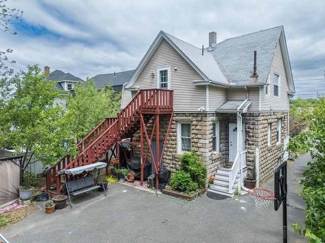 70 Riverdale St, West Springfield, MA 01089 - back of property with a patio area, a chimney, and stone siding