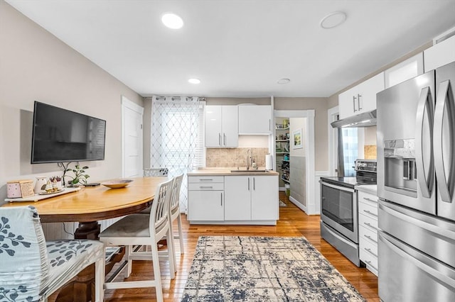 70 Riverdale St, West Springfield, MA 01089 - kitchen with stainless steel appliances, under cabinet range hood, a sink, white cabinetry, and light wood-style flooring