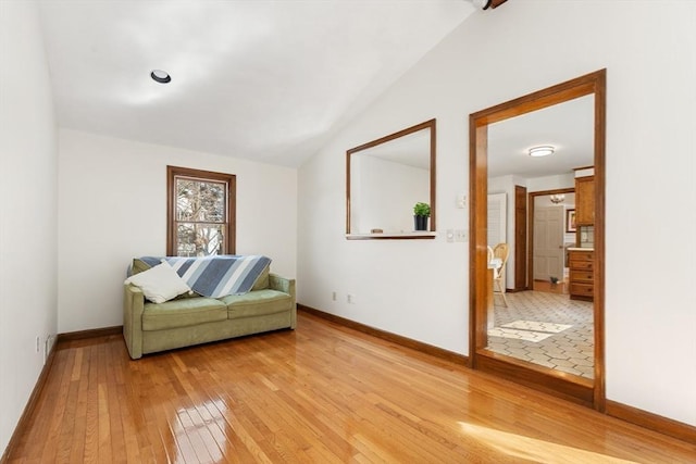 sitting room featuring vaulted ceiling, light wood-style flooring, and baseboards