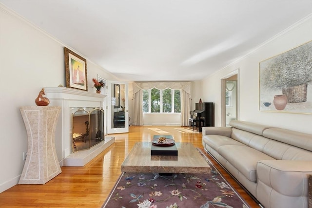 living area featuring a fireplace, crown molding, baseboards, and wood finished floors