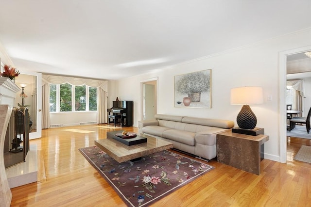 living area with crown molding, light wood-style flooring, and baseboards