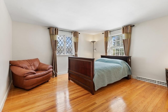 bedroom with light wood-style floors, baseboards, and baseboard heating