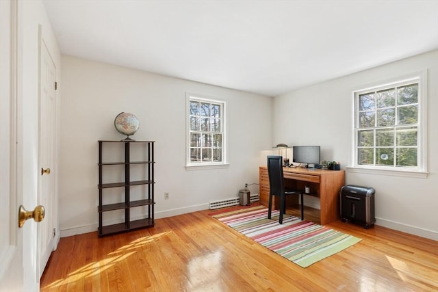 office space featuring a baseboard radiator, wood finished floors, and baseboards