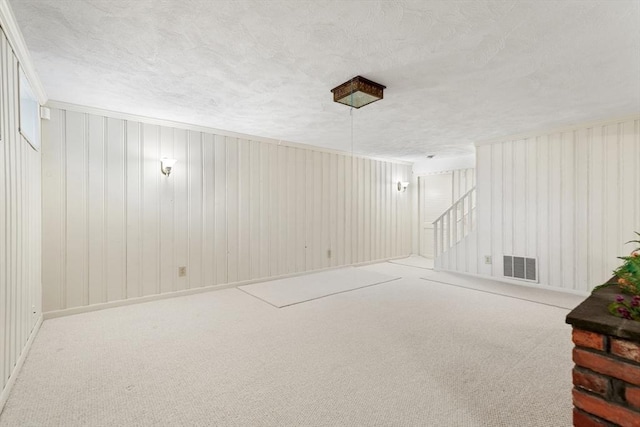 basement featuring stairway, carpet, visible vents, and a textured ceiling