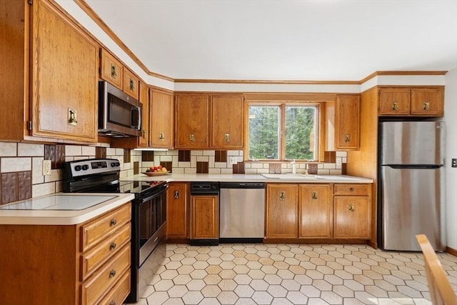 kitchen with appliances with stainless steel finishes, brown cabinets, light countertops, crown molding, and a sink