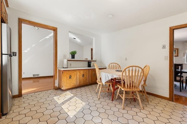 dining space featuring baseboards, visible vents, and vaulted ceiling