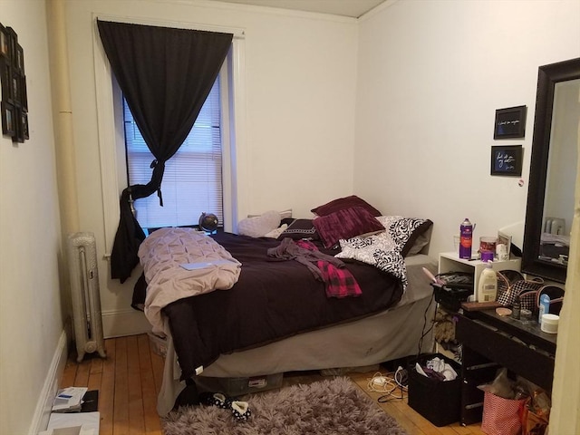 bedroom with radiator heating unit and light wood-type flooring