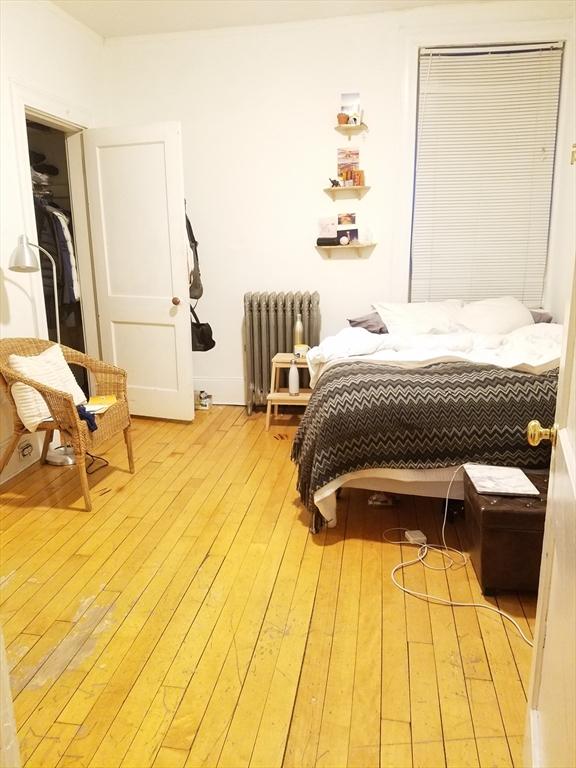 bedroom featuring radiator heating unit and light wood-type flooring