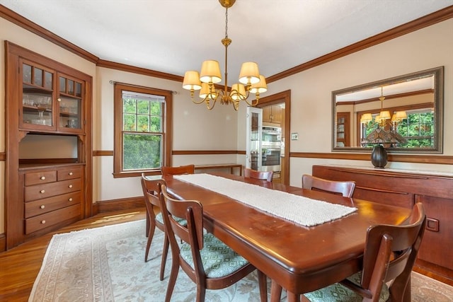dining room with a chandelier, crown molding, and wood finished floors