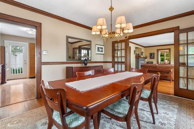 dining area featuring wood-type flooring, a chandelier, and ornamental molding