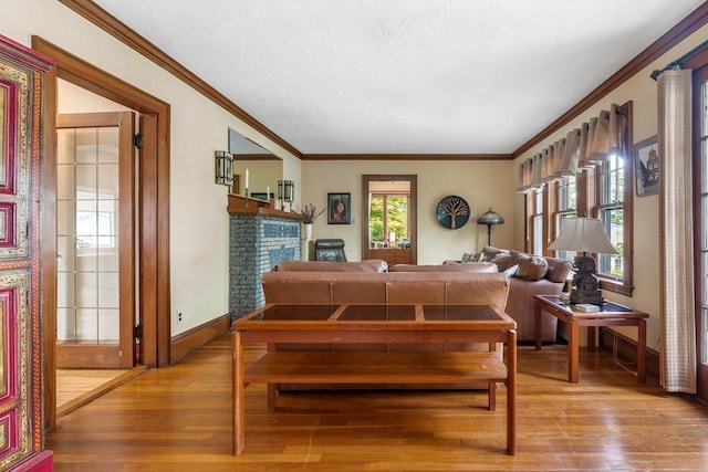 living area featuring wood finished floors, baseboards, ornamental molding, and a textured ceiling