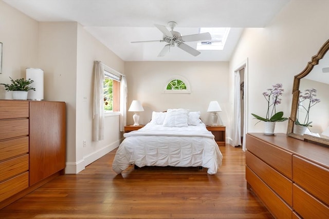 bedroom with wood finished floors, baseboards, a skylight, and ceiling fan
