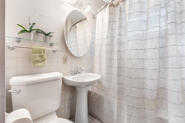bathroom featuring tile walls, toilet, decorative backsplash, curtained shower, and a sink