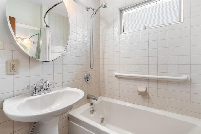 bathroom with tile walls, bathtub / shower combination, a sink, and tasteful backsplash
