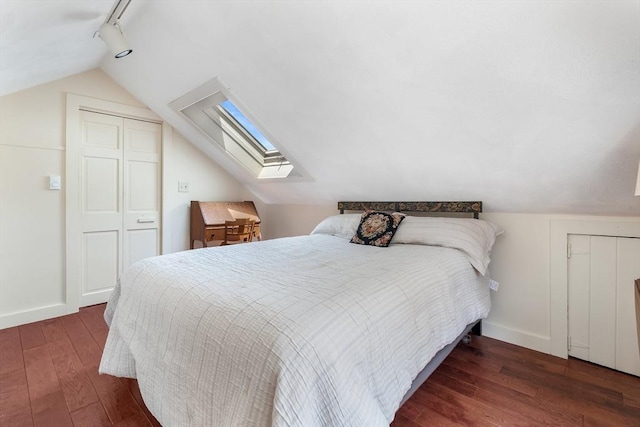 bedroom with a skylight, lofted ceiling, wood finished floors, baseboards, and track lighting