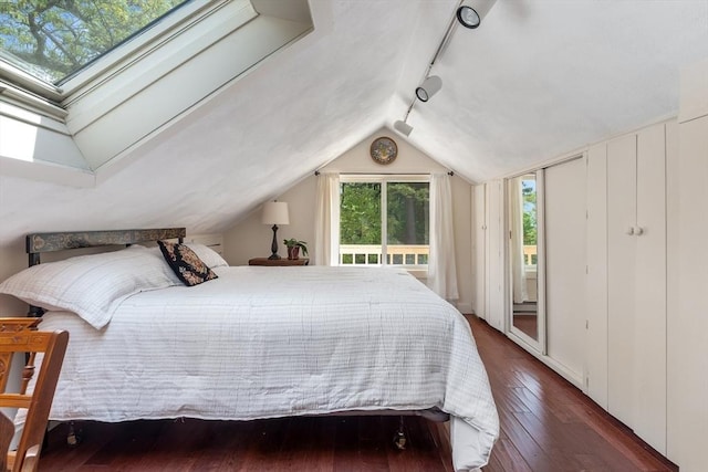 bedroom with access to outside, hardwood / wood-style flooring, vaulted ceiling, and rail lighting
