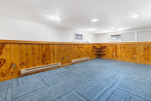 empty room with a baseboard heating unit, carpet, a wainscoted wall, and wooden walls