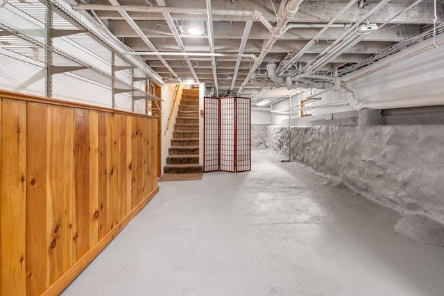 unfinished basement featuring stairway and wooden walls