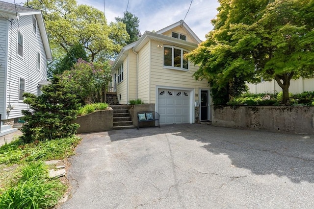 view of front of property featuring an attached garage, driveway, and stairs