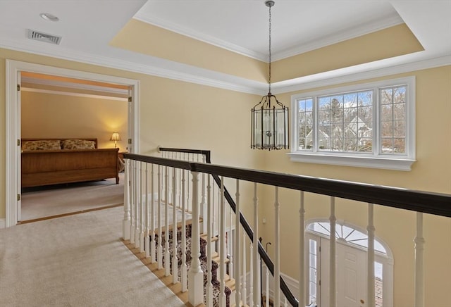 corridor featuring a notable chandelier, light colored carpet, and a raised ceiling