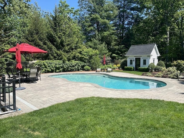 view of pool featuring a lawn, an outbuilding, and a patio area