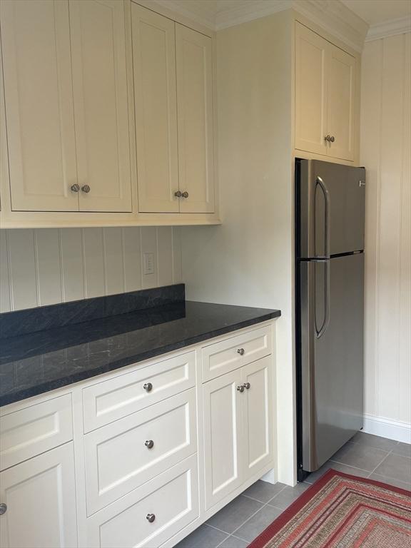 kitchen featuring tile patterned floors, stainless steel refrigerator, and white cabinetry