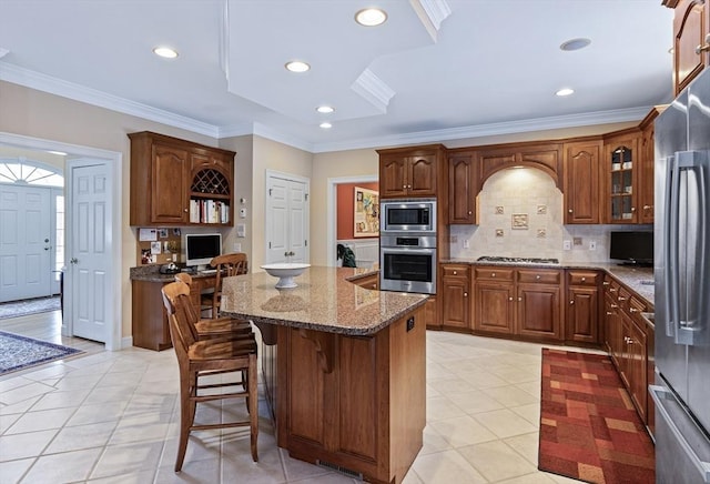 kitchen featuring appliances with stainless steel finishes, a breakfast bar, a kitchen island, stone countertops, and backsplash