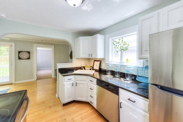 197 Eastern Ave, Worcester, MA 01605 - kitchen with appliances with stainless steel finishes, arched walkways, a sink, and light wood-type flooring
