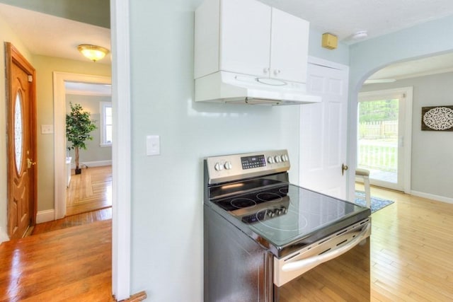 197 Eastern Ave, Worcester, MA 01605 - kitchen with stainless steel electric range oven, under cabinet range hood, white cabinets, arched walkways, and baseboards