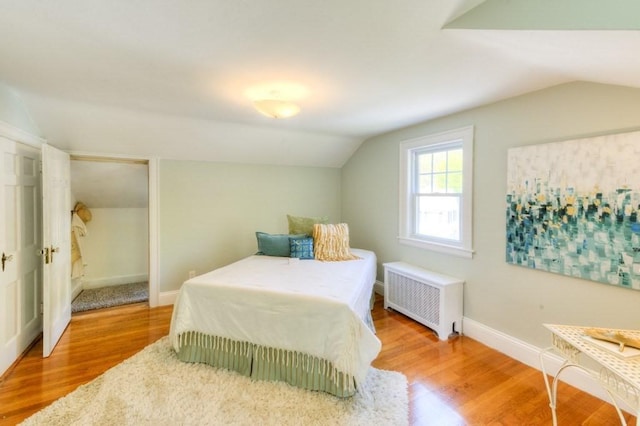 197 Eastern Ave, Worcester, MA 01605 - bedroom featuring radiator heating unit, vaulted ceiling, wood finished floors, and baseboards